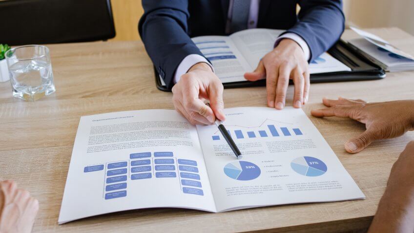 Banker explaining pie chart to couple at home.