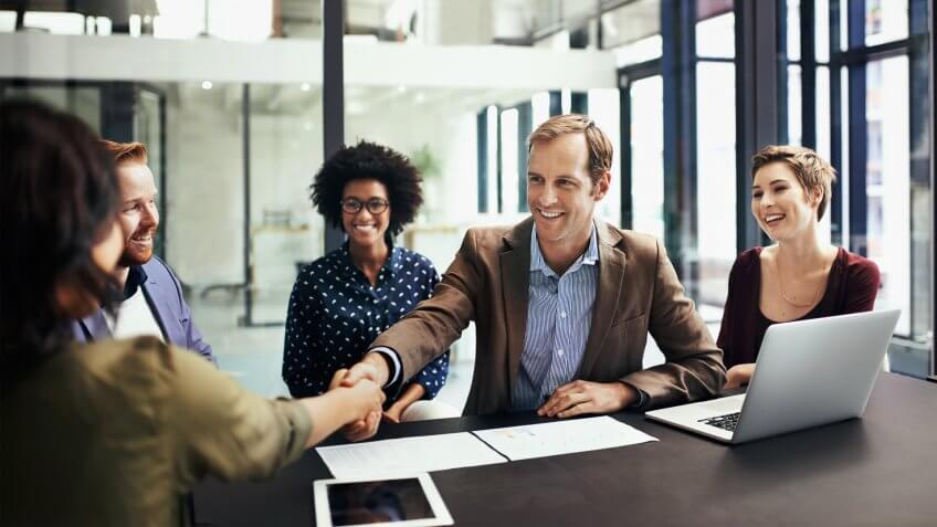 Shot of colleagues shaking hands during a meeting at work.