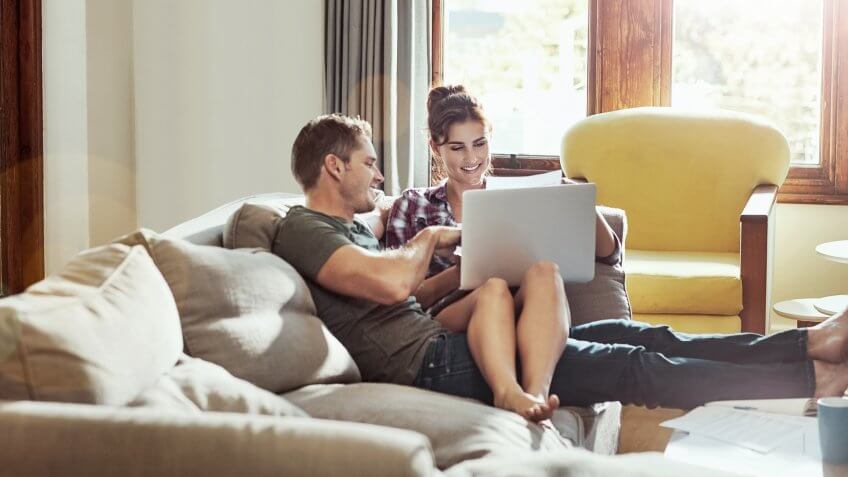 Shot of a young couple using a laptop together on the sofa at home.