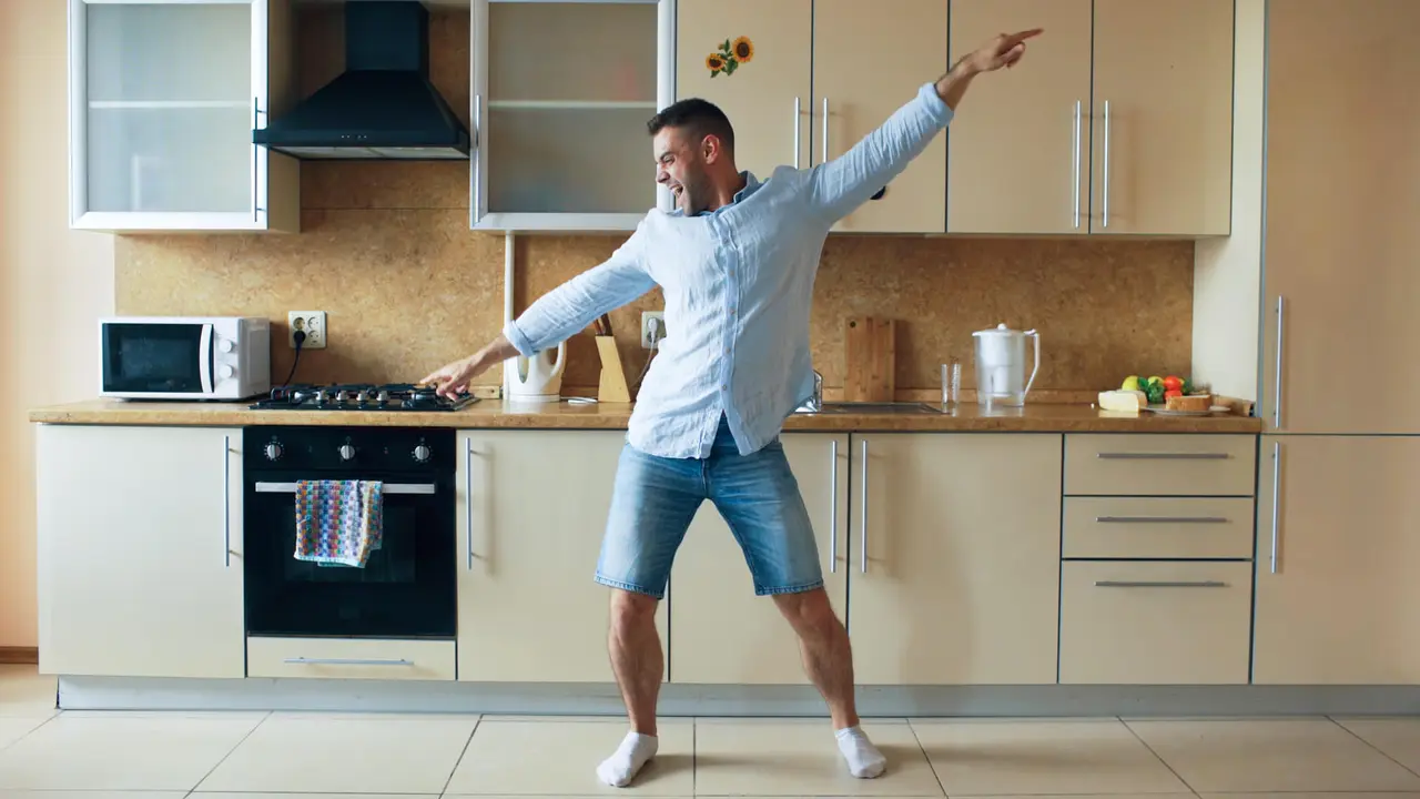 Handsome young funny man dancing in kitchen at home in the morning and have fun on vacation.