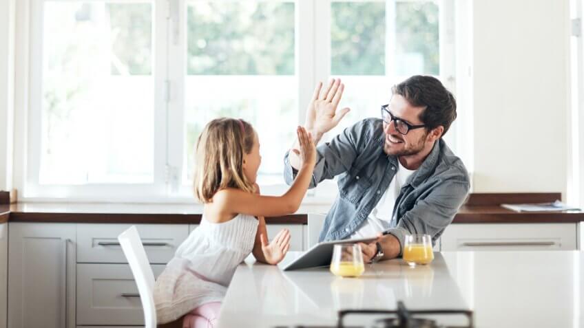 Shot of an adorable little girl using a digital tablet with her father at home.