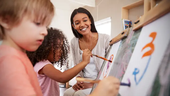 Teacher At elmentary School Helping Children in Art Class.
