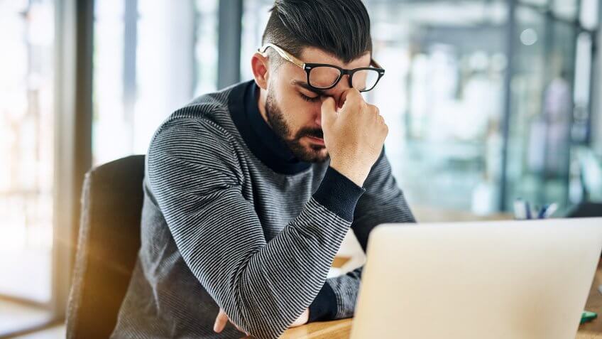 Shot of a young designer looking stressed out while working in an office.