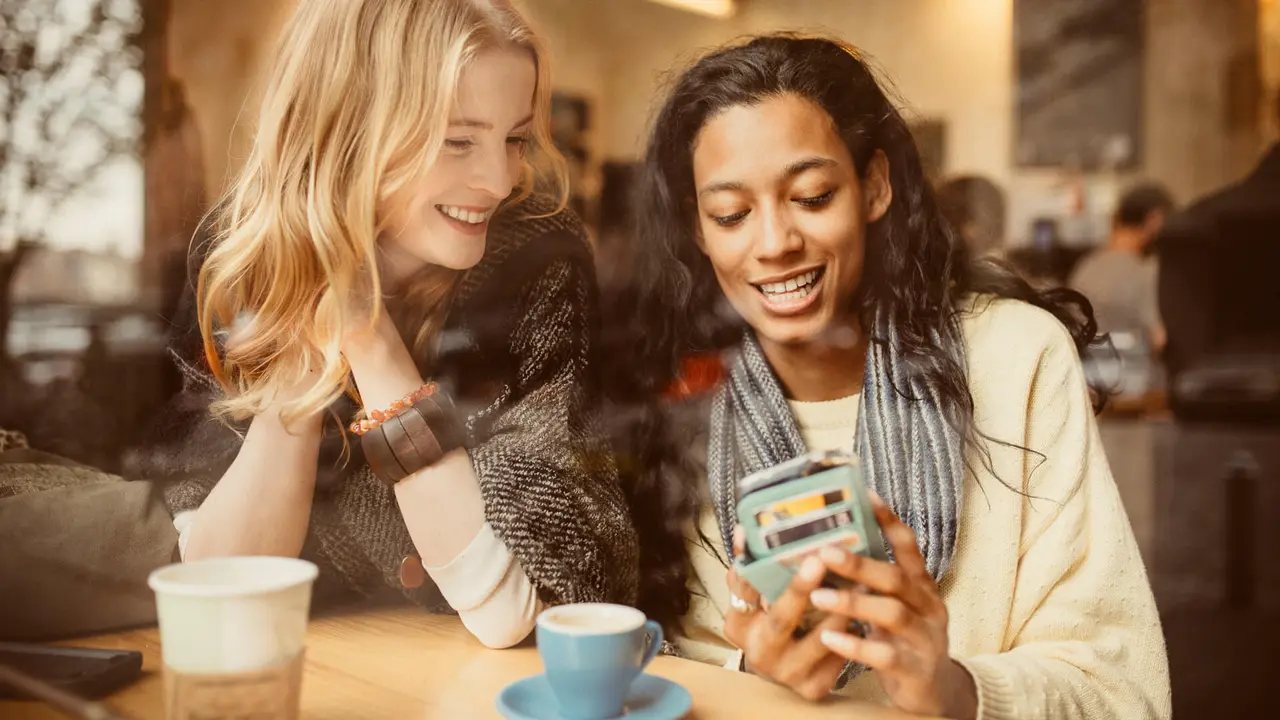 Girlfriends using Smartphone in Coffeeshop.