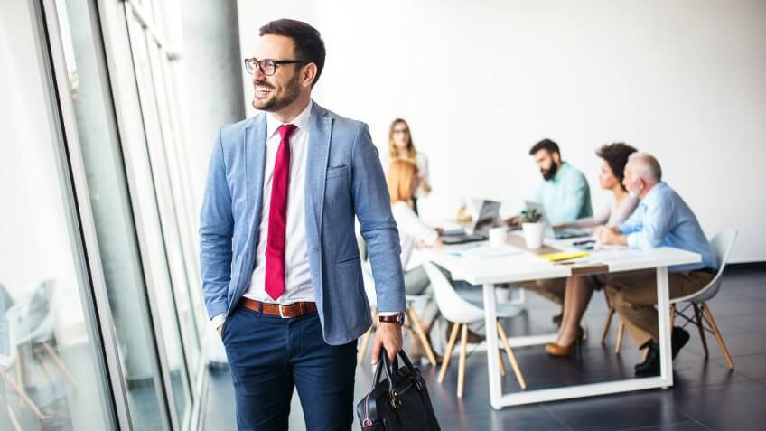 Handsome young businessman walking away from work and going home from modern office.