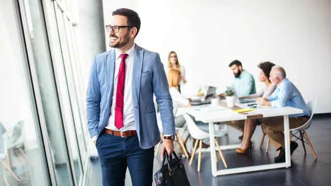Handsome young businessman walking away from work and going home from modern office.