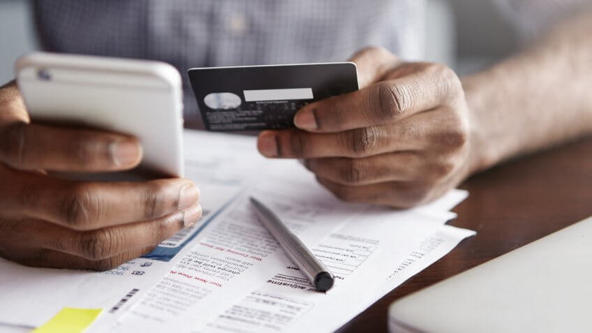 man holding a credit card and iPhone