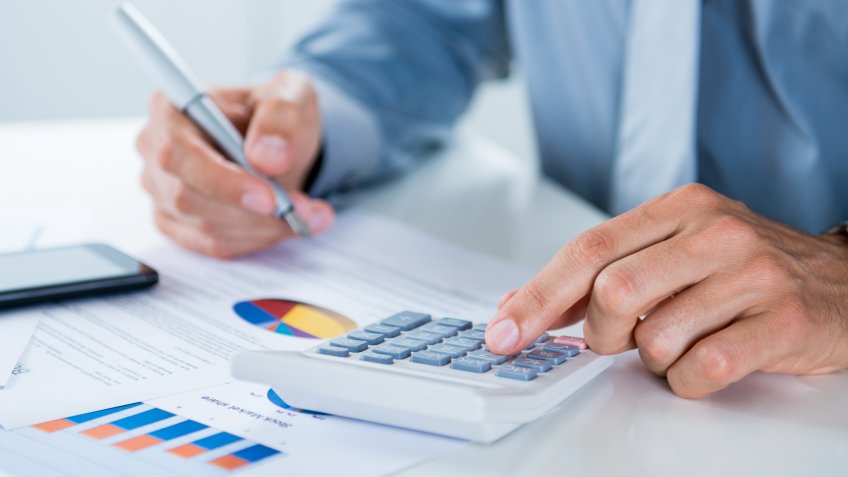 man using calculator and graphs