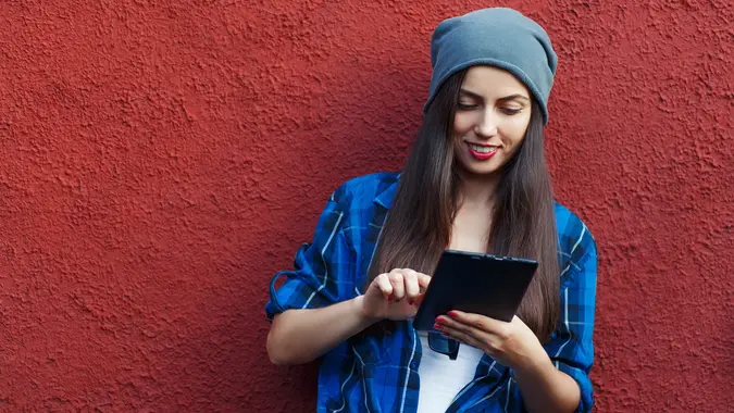 Portrait of a cheerful hipster woman holding tablet computer.