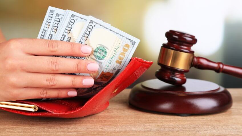 Gavel and hand holding money in wallet on wooden background.