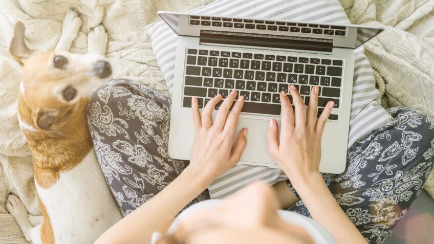 Beautiful woman is sitting on the bed listening to music in headphones using a mobile phone.