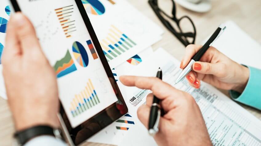 Two professionals in office, one young female and one male, in formal clothing, dealing with finance, financial issues, investments, and market analysis.