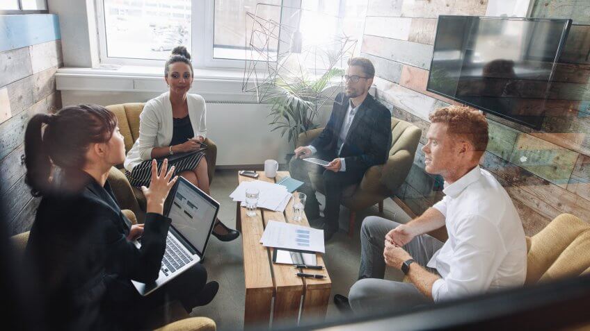 Four young business colleagues meeting in modern office.