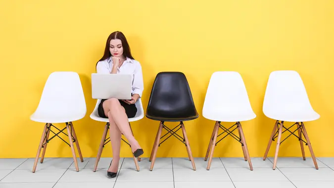 Young woman waiting for job interview on yellow wall background.