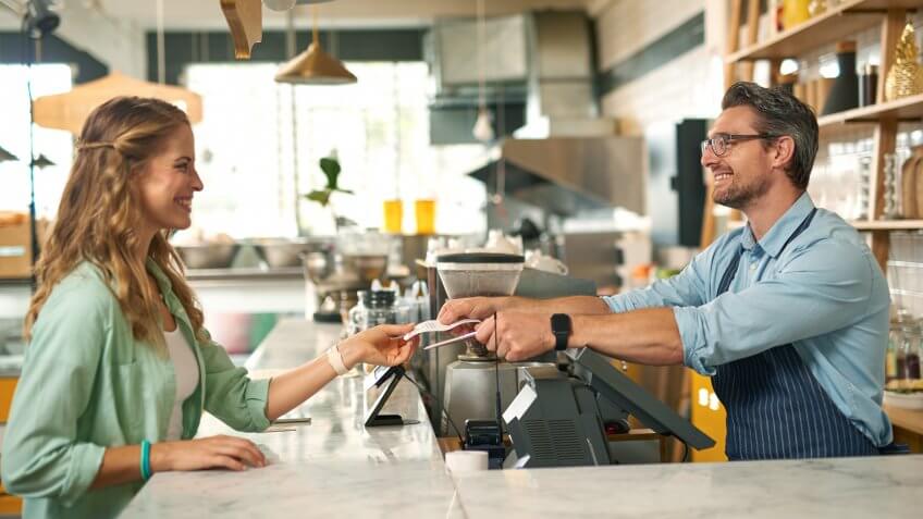 Shot of woman paying for coffee with credit card at cafe.