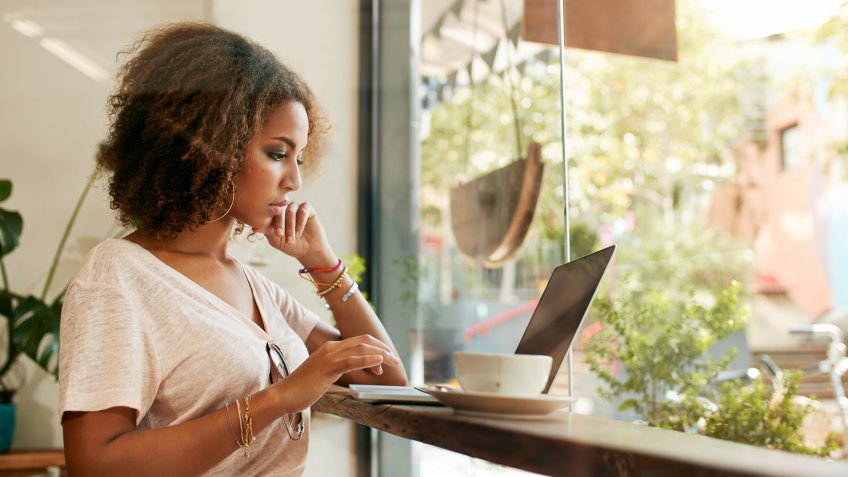 Young black female at cafe using laptop.