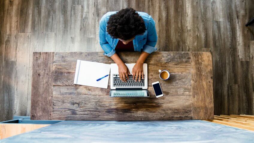 Overhead view of a woman using a computer whilst working/ studying in a modern looking room.