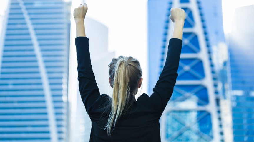 Business success - Celebrating businesswoman overlooking the city center high-rises.