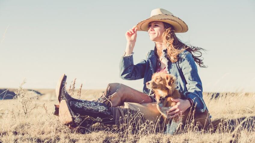 A cowgirl sitting on a grassy prairie