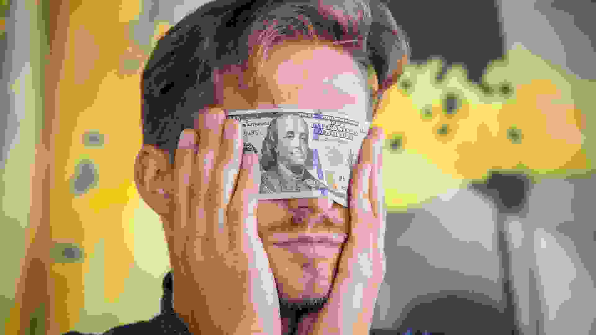 Man blindfolds eyes with 100 dollar bill