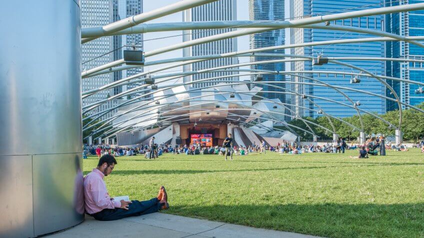 Chicago, IL, July 17, 2017: A young man reads, waiting for an event to begin at Millennium Park in Chicago.