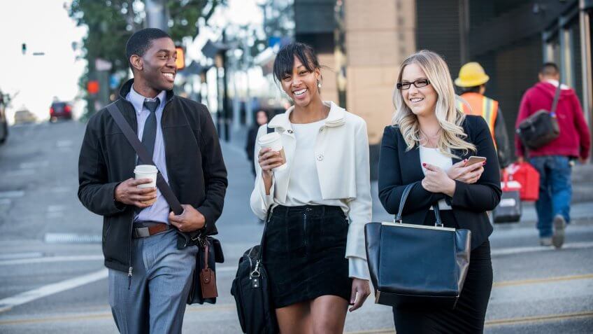 millennial office workers crossing a city street at the end of their work day with coffee.