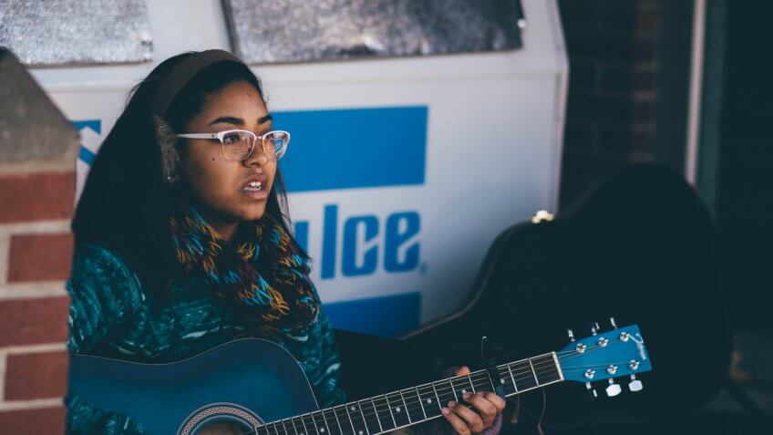 Millennial playing her guitar somewhere in Ohio