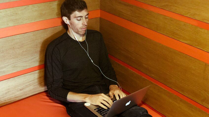 Millennial using laptop in corner of office
