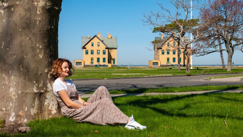 Woman tourist is sitting in the park near the tree.