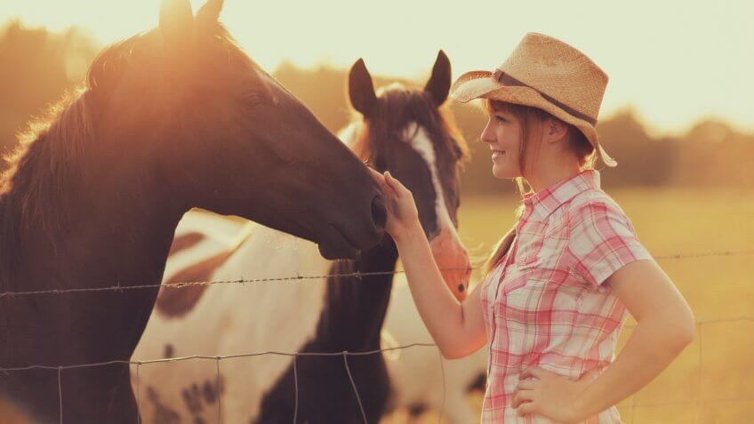 A young western girl spends time with her horses on the farm.