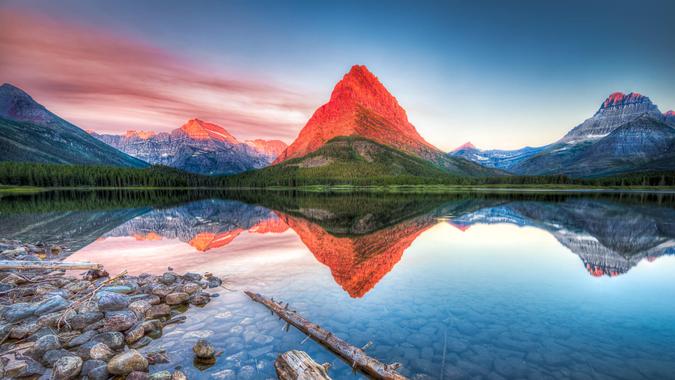 Stunning reflections on Swiftcurrent Lake in northern Montana at sunrise.