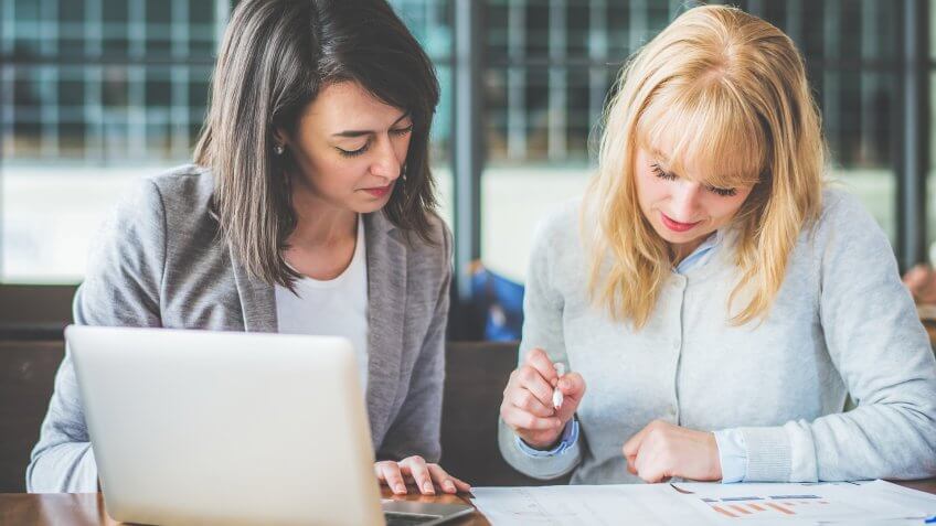 Two businesswoman working together with laptop and paperwork at coffee shop, color tone effect.