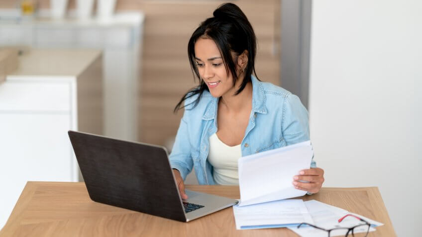 Portrait of a woman at home paying her bills online - home finances concepts.