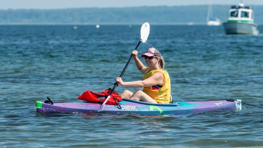 Blonde woman in kayak paddling in charity race across Narragansett Bay, from Newport to Jamestown, Rhode Island.