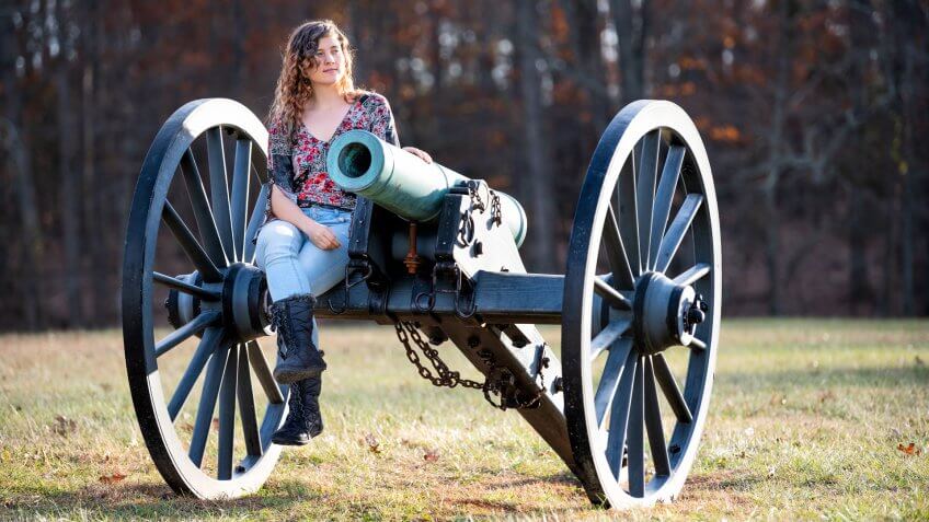 Young woman sitting on old cannon in Manassas National Battlefield Park in Virginia where Bull Run battle was fought