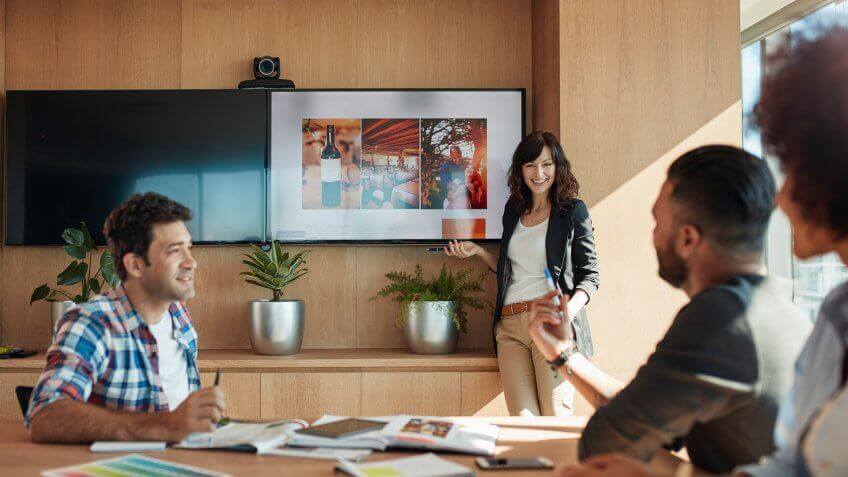 Female coworker making presentation during business meeting in office.
