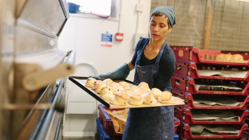 A baker removes scones from a commercial bread oven.