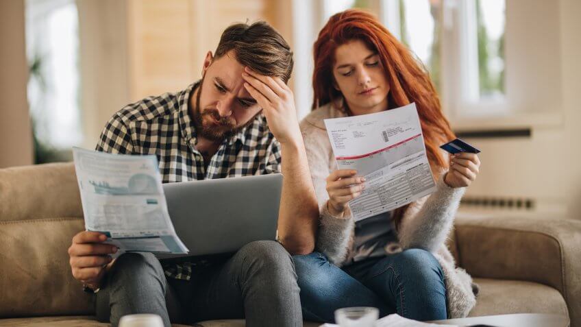 Worried couple feeling frustrated while have to pay their bills over Internet.