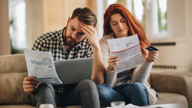 Worried couple feeling frustrated while have to pay their bills over Internet.
