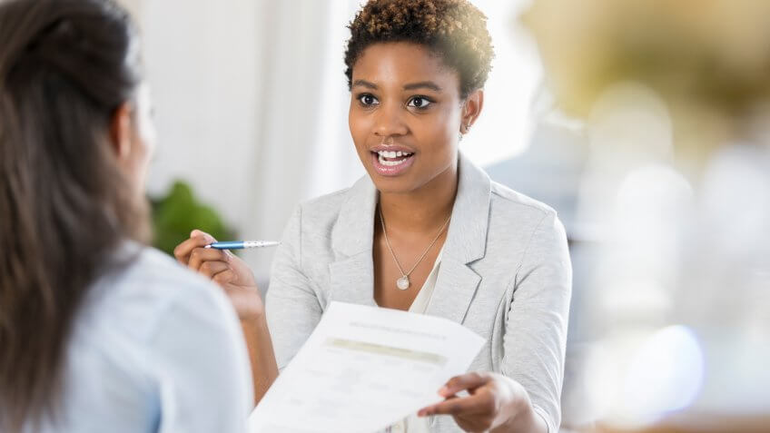 Young businesswoman has a serious expression on her face while discussing a document with a female colleague.