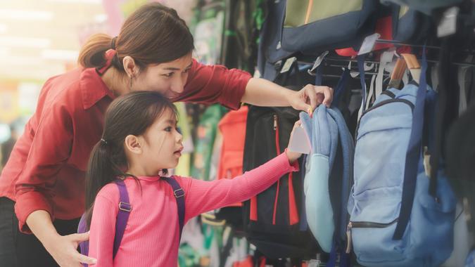 Back to school concept, mother or father and little girl buying school backpack or bag in store, selective focus.