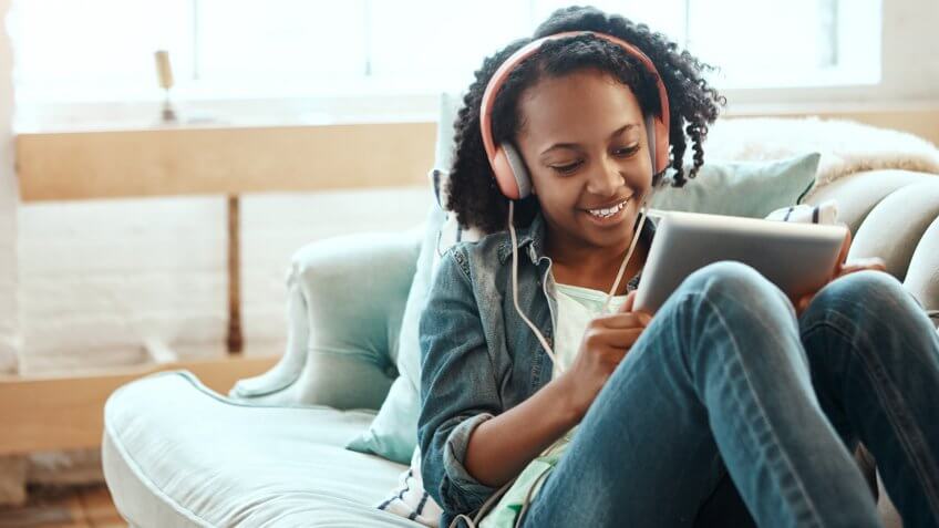 Cropped shot of a young girl chilling on the sofa with her tablet indoors.