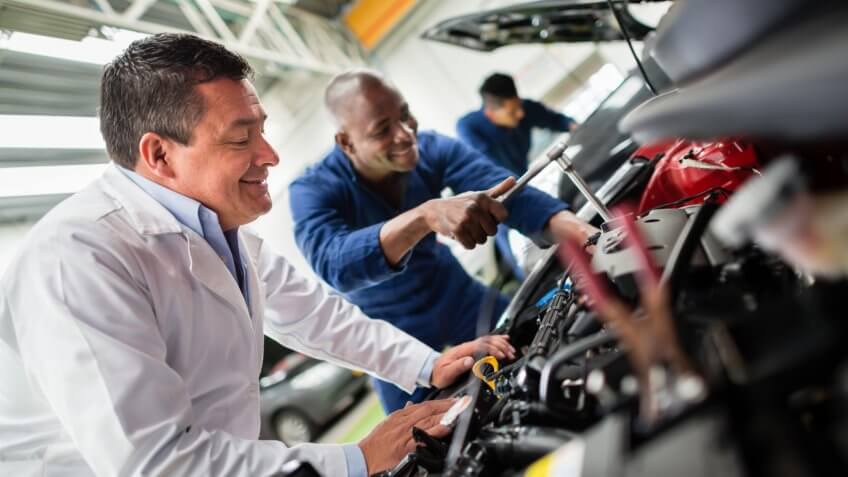 Group of mechanics fixing a car at the garage.
