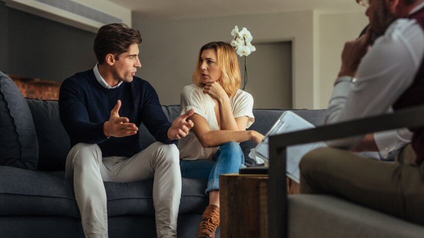 Couple arguing during therapy session with psychologist.