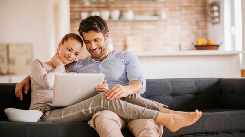 Close up of a happy young couple using laptop at home.