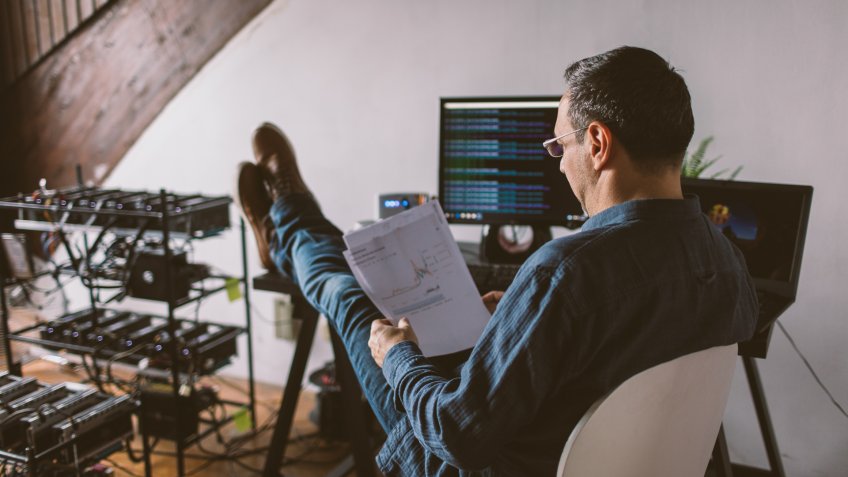 Mature man cryptocurrency mining in his office.
