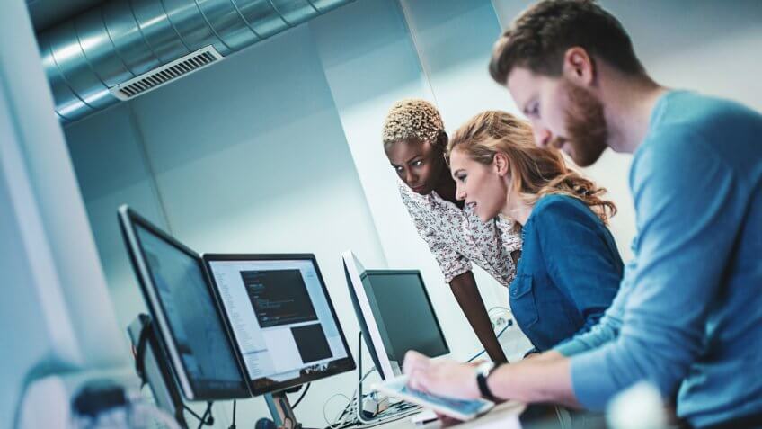 Closeup side view of group of software developers working late at IT office.