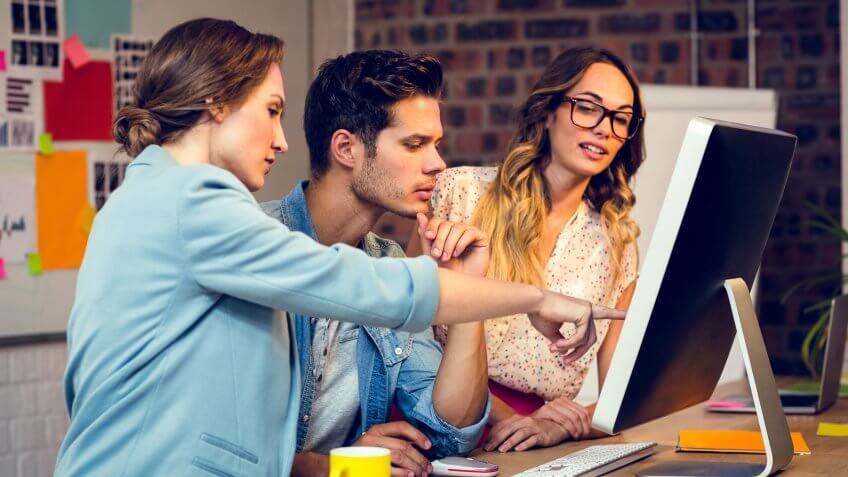 Graphic designers discussing over computer in office.