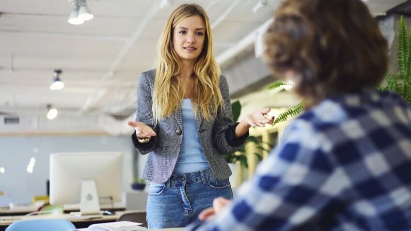 Professional female blonde HR manager of company hiring young male IT programmer to develop software explaining detail and requires to job during meeting on first working day in modern office.