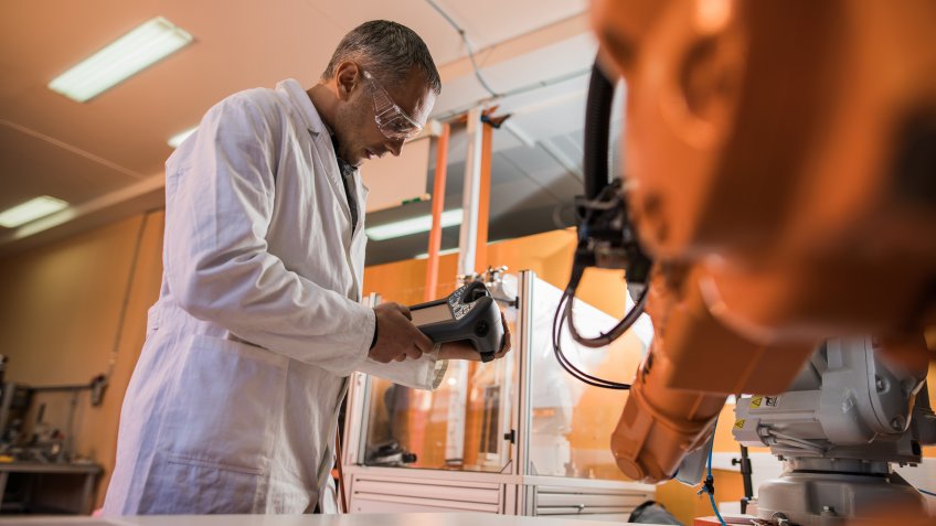Low angle view of scientist programming automated robot during scientific experiment in a laboratory.